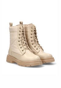 Botas de combate beige con caña acolchada, parte delantera con cordones y suela gruesa y texturizada. Incluyen tiradores para facilitar su uso y están hechas de material duradero.