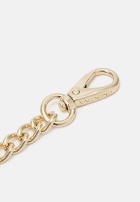 Złoty metalowy łańcuszek o dużym wzorze ogniwa, z zapięciem typu lobster oraz wygrawerowanym napisem "VALENTINO" na elemencie metalowym.