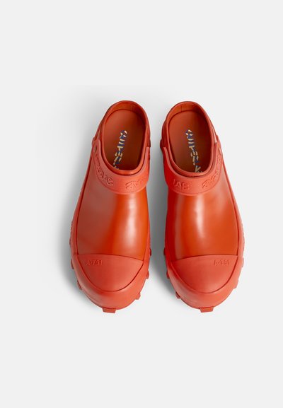 Orange gummistövlar med en slät yta, rund tå och baksidesdesign. Har präglad branding och en tjock sål med mönstring.