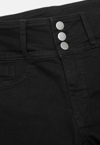 Mustat denimpantsit, joissa on korkea vyötärö, kolme metallista nappia ja hillitty ommelkoristelu. Tasainen pinta ja tiukka muotoilu.