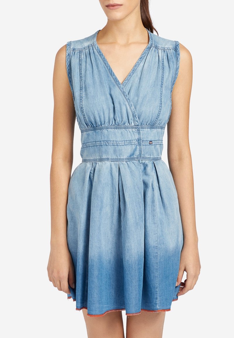 Sukienka dżinsowa z dekoltem w kształcie litery V, bez rękawów i dopasowanym stanem. Jasnoniebieski kolor z plisowanym dołem i pomarańczowymi przeszyciami na krawędzi.