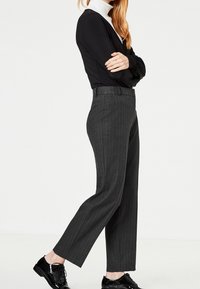 Tmavě šedé pruhované kalhoty s přizpůsobeným střihem, s hladkou texturou a moderním střihem, v kombinaci s černými šněrovacími botami.