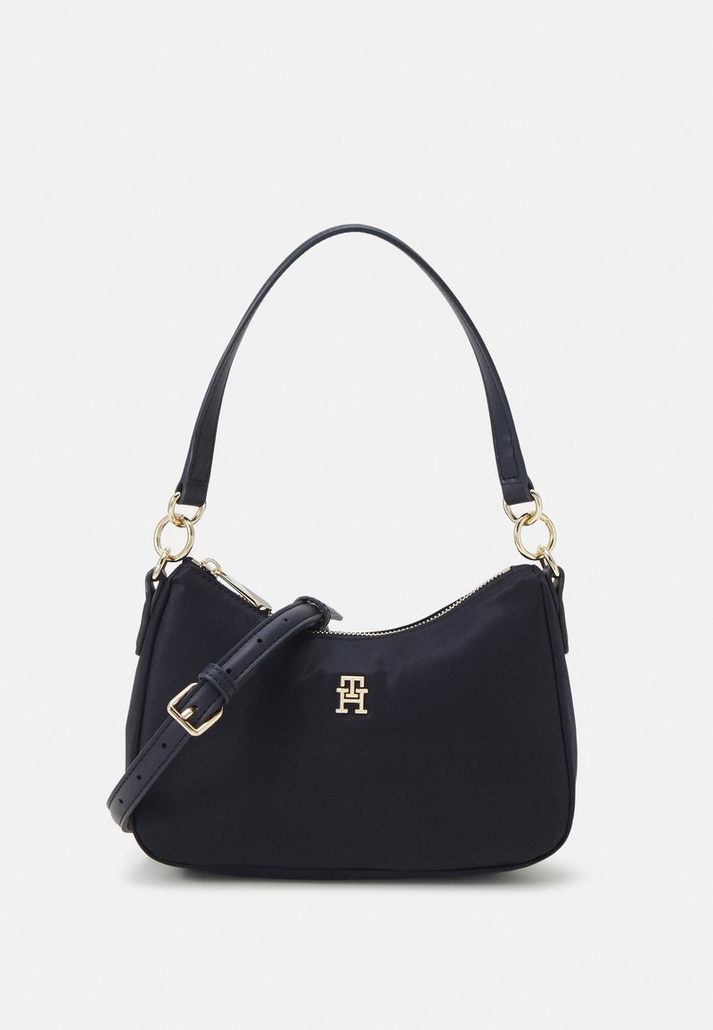 Sac bandoulière noir avec sangle ajustable, ferrures dorées, fermeture éclair et petit emblème doré du logo centré à l'avant.