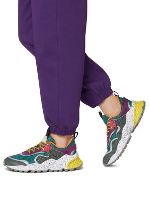 Multicolored sneakers featuring a mix of textures and patterns, with a gray base, purple accents, speckled white midsole, and yellow sole.