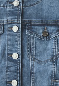 Jeansjacka med blåtvätt, silverfärgade knappar och synlig söm. Har två framfickor med lock och en något urtvättad yta.