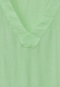 Ljusgrön topp med V-halsdesign och subtila strukturerade ränder som ger ett mjukt och flödande utseende.