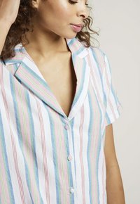 Chemise à manches courtes rayée avec des lignes bleues, roses et vertes, rehaussées de touches rouges, un col à encoches et un devant à boutons. Tissu texturé.