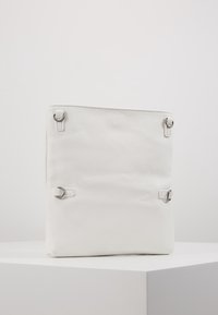 Borsa bianca in pelle con superficie testurizzata. Caratterizzata da accessori in metallo argentato e anelli laterali. Forma quadrata con design minimalista.
