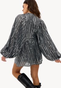 Robe plissée noire et argentée avec des manches ballons longues et une taille cintrée, dotée d'un motif texturé et d'une jupe évasée.