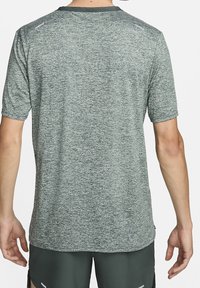 Camiseta atlética de manga corta en verde jaspeado, diseñada con tejido que absorbe la humedad, cuello redondo y sutiles acentos en los hombros.