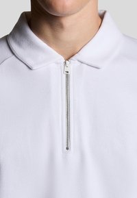 Weißer Fleece-Pullover mit einem Reißverschluss und einem flachen Kragen. Verfügt über eine glatte Textur und ein minimalistisches Design für die Freizeit.