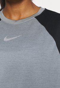 Nike-tröja med en ljusgrå kropp och svarta raglanärmar. Har en rund halsringning och en liten silverfärgad logotyp på br�östet.
