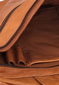 Rudos odos kuprinė vidus su užtrauktuku, pasižyminti lygiu paviršiumi ir tvirta siuvimo kokybe, su tamsiu audiniu viduje.