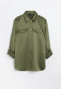 Olivgrön skjorta med knappar i en smidig tyg, med spetsig krage, två bröstfickor, uppkavlade ärmar och metallknappar.
