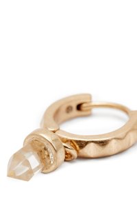 Boucle d'oreille en or avec une surface texturée et un cristal clair et pointu suspendu à un attachement circulaire.