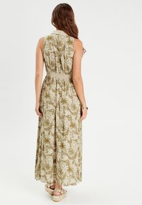 Maxi dress featuring a floral pattern in olive green and cream, with a fitted waist and sleeveless design, made from lightweight fabric.