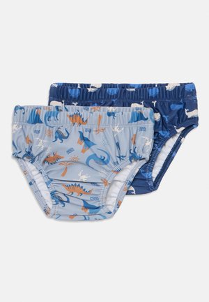 Dos pares de bañadores infantiles en tonos azules. Uno tiene un estampado de dinosaurios, el otro presenta un diseño de ballenas, ambos con cinturas elásticas.