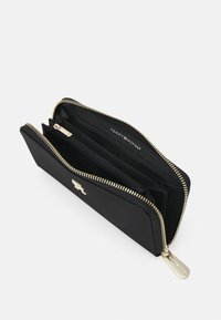Zwarte ritsportemonnee met een gouden rits, meerdere vakken en een klein logo-detail aan de binnenkant. Gemaakt van glad, duurzaam materiaal.