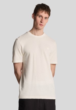 T-shirt bianco testurizzato con collo rotondo e maniche corte, caratterizzato da un delicato motivo a nido d'ape e un piccolo logo sul petto.