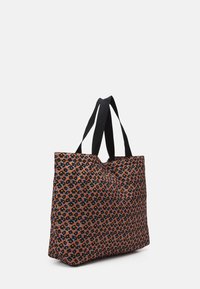 Sac fourre-tout en tissu marron avec un motif floral en noir, bleu et jaune. Poignées en tissu noir. Forme rectangulaire.