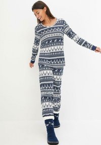 Un ensemble de pyjama à motifs bleu marine et blanc comprenant des manches longues et un pantalon avec un design de fêtes, accompagné de chaussettes douillettes bleues assorties.