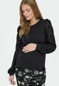 Must värviline dressipluus, millel on tekstuuriga mustad lillad ja sädelevad pikad varrukad, ümar kaelus ja sobitatud varrukate mansetid, koos lillemustritega seeliku jaoks.