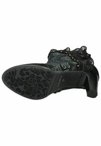 Stivaletto nero con sovrapposizione di pizzo, bordo a volant e borchie decorative. Suola nera texturizzata con dettaglio floreale. Design con tacco.