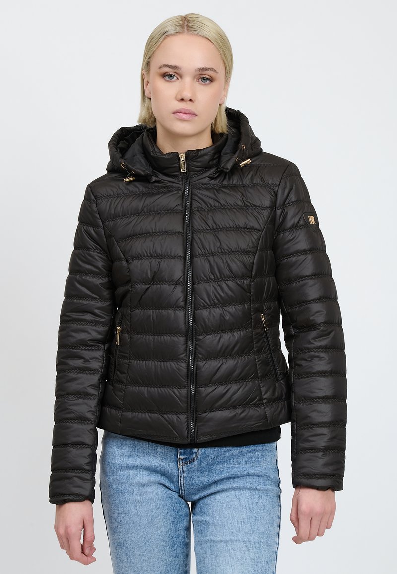 Giacca invernale nera, trapuntata e con cappuccio, caratterizzata da zip e dettagli dorati. Ha un design aderente e maniche lunghe con polsini elasticizzati.