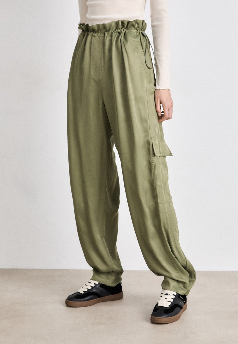 Olive green cargo pants with a gathered elastic waistband, side pockets, and a loose fit, made from smooth, lightweight fabric.