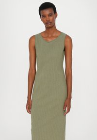 Rochie maxi verde măsliniu, cu decolteu rotund, fără mâneci și o siluetă ajustată, realizată dintr-un material texturat.