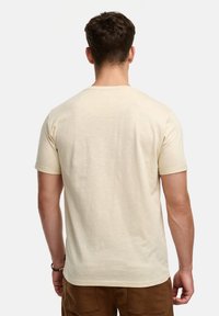Camiseta de manga corta para hombre en color beige claro, con cuello redondo y una tela suave, ligeramente texturizada. Costuras sutiles a lo largo de los hombros.