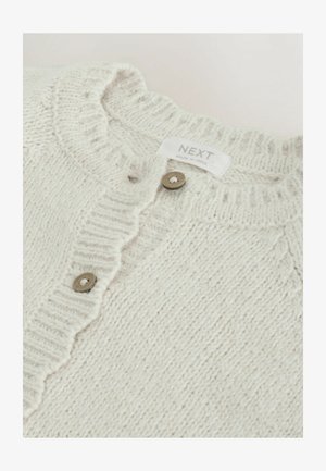 Hellbeige gestrickte Strickjacke mit einem strukturierten Muster, geripptem Kragen und fünf runden braunen Knöpfen. Das Etikett lautet "NEXT, hergestellt in Indien."