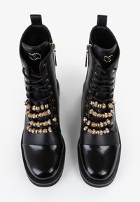 Stivali alla caviglia in pelle nera con perline decorative color oro sui lacci, chiusura con zip, punta arrotondata e punta lucida.