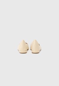Beige ballet flats with a textured, glossy finish, pointed toe design, minimal heel, and subtle stitching details.