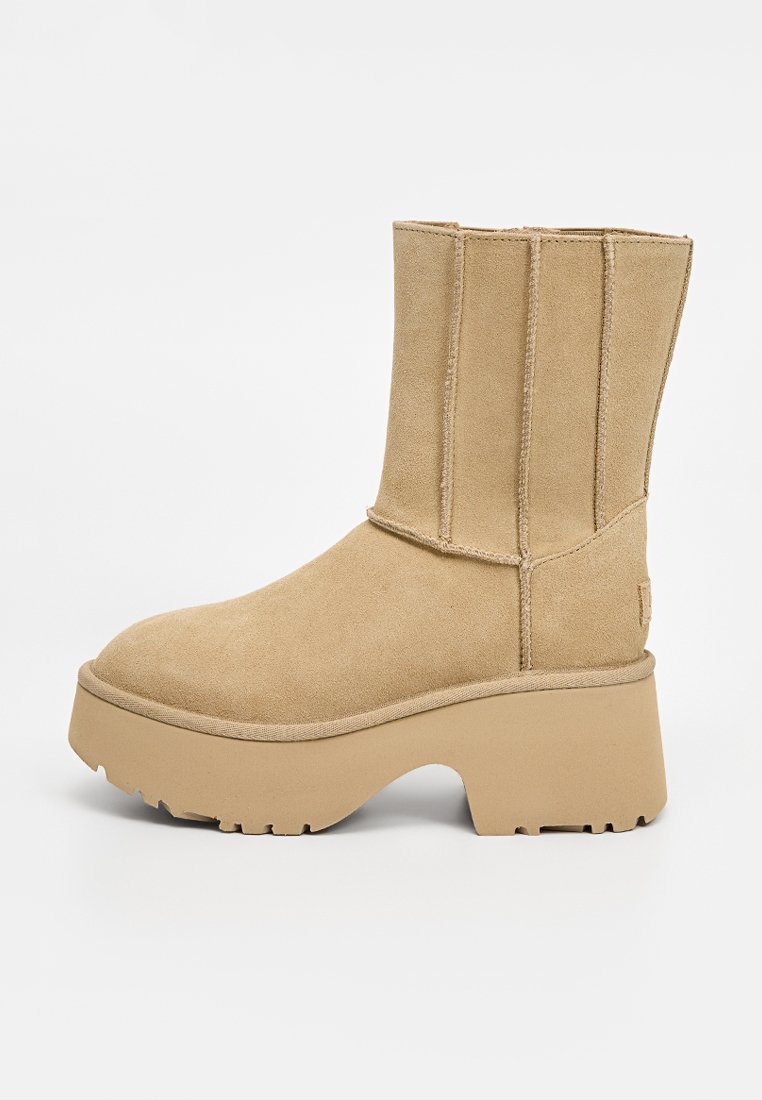 Beige ankelskortsstövel i mocka med rund tå och vertikala sömdetaljer. Har en tjock plattformssula med texturerat grepp.