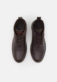 Brown leather lace-up boots with textured surface, round toe, and stitched detailing. Features a pull tab and contrasting brown top section.