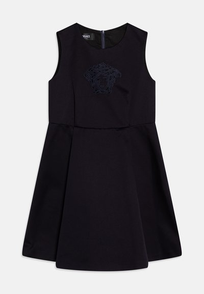 Must Black sleeveless dress with a flared skirt, featuring an embroidered Medusa logo on the front and a zipper closure at the back.