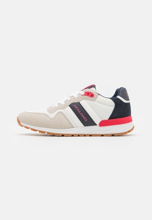 White and beige sneakers with navy and red accents, featuring suede and mesh materials, a rubber sole, and brand logo on the side.