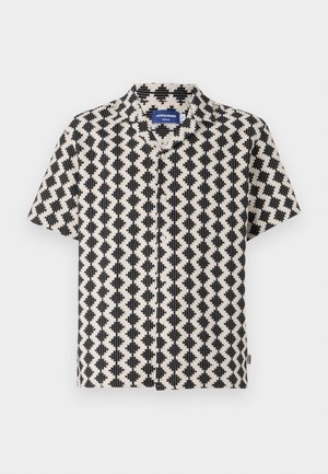 Chemise à manches courtes avec un motif géométrique crème et noir. Dotée d'un col et d'une fermeture à boutons sur le devant. Fabriquée en tissu léger.