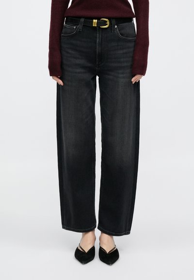 Μαύρα τζιν με φαρδιά ποδιά και μέση μέτριας ανόδου, διαθέτουν κλασικό σχεδιασμό με πέντε τσέπες και κρυφό κούμπωμα με κουμπιά. Συνδυάζονται με μαύρη ζώνη και μυτερά παπούτσια.