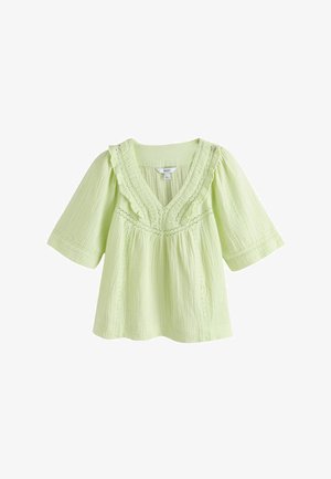 Világoszöld, texturált blúz V-nyakkivágással, fodros csipke szegéllyel, könyökig érő ujjakkal és laza szabással.