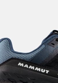 Mørkeblå og sorte træningssko med en tekstureret mesh-overdel, en robust sål og reflekterende detaljer; mærket med "Mammut."