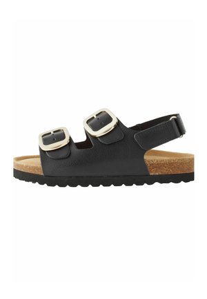 Svart sandal med två silverfärgad spännen, korkfotbädd och texturerad gummisula. Har justerbart bakrem för en säker passform.