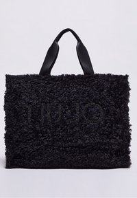 Czarna torba na ramię z sztucznego futra o teksturowanej powierzchni, z miękkim materiałem, górnymi czarnymi uchwytami i błyszczącym logo "LIU•JO" z przodu.