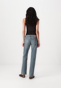 Jeans din denim ușor albastru, cu talie înaltă și un finisaj ușor decolorat, având două buzunare la spate și o etichetă bej deasupra liniei taliei.