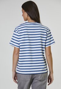 Camiseta blanca con rayas horizontales azules, cuello redondo clásico, mangas cortas y un corte relajado. Material de algodón suave.