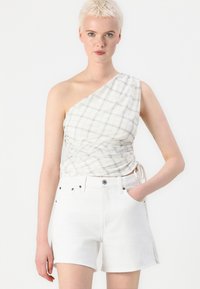 One-shoulder top in lightweight fabric features a checkered pattern in white and gray, paired with high-waisted white denim shorts.