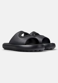 Zwarte leren slip-on sandalen met een open teen, voorzien van twee ronde uitsparingen op de bovenkant en een dikke rubberen zool met een gestructureerde grip.