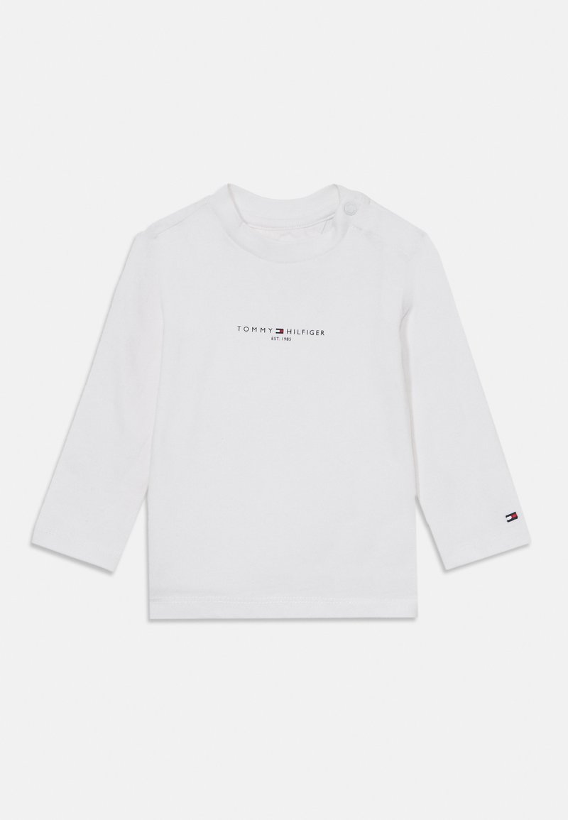 Weißes Langarmbabyschirt mit dem "Tommy Hilfiger EST. 1985" Logo auf der Brust und kleinem Flaggenlogo am Bündchen des linken Ärmels.