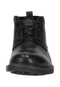 Bottine en cuir noir avec bout rond, fermeture à lacets à l'avant, et languette de tirage à l'arrière, vue de face sur fond blanc.